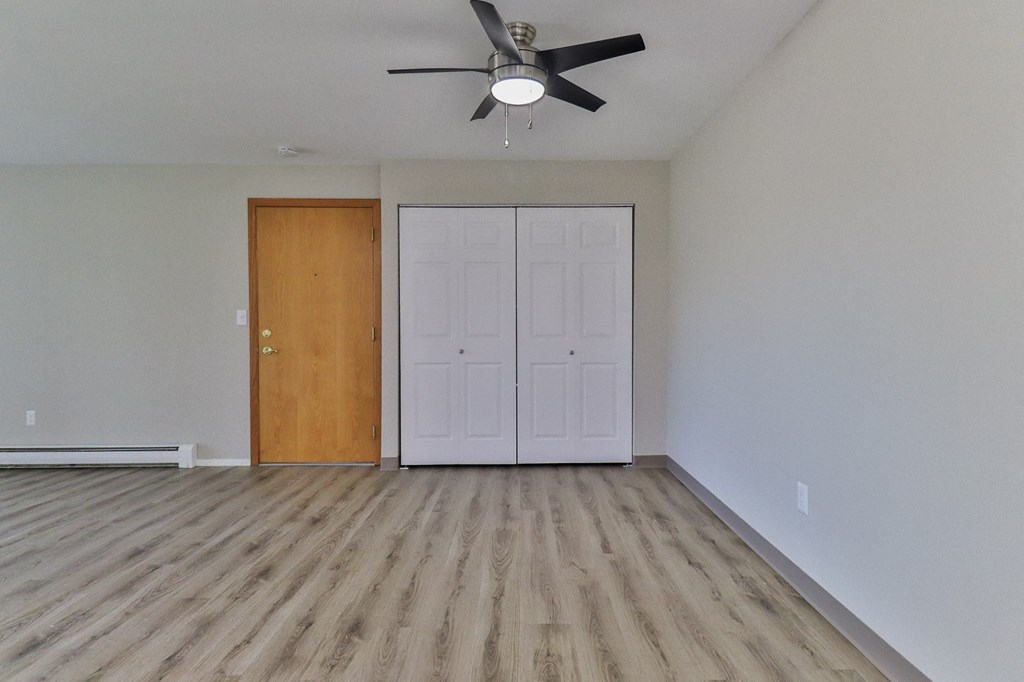 an empty living room with wood floors and a ceiling fan