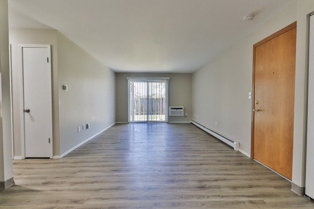 an empty living room with wood floors and a door to a balcony