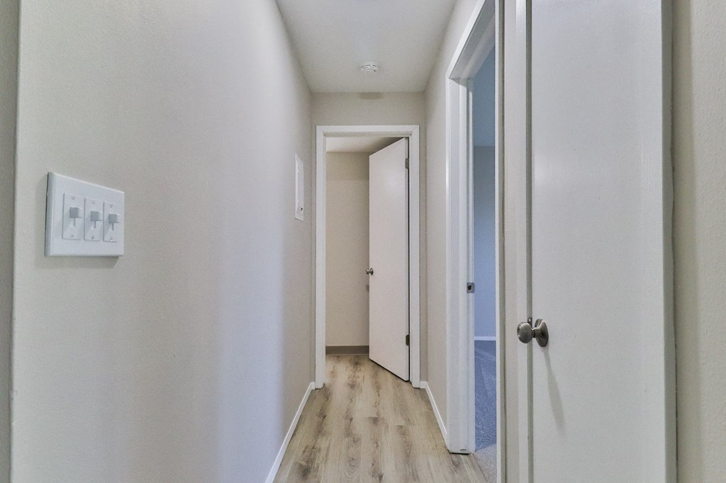 a hallway with white walls and wood floors and a white door