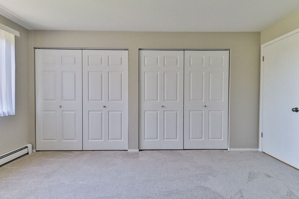 an empty room with white closets and a carpeted floor