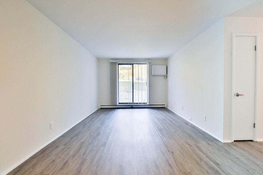 an empty living room with wood flooring and a window