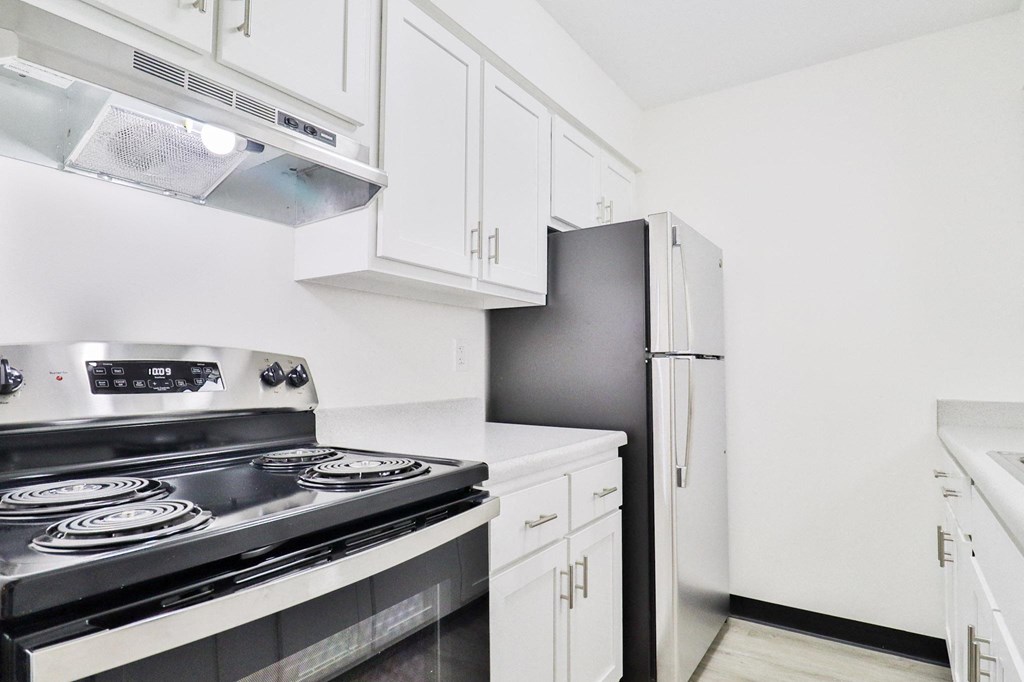 a kitchen with white cabinets and black appliances and a refrigerator