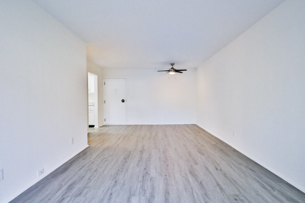 an empty living room with white walls and a ceiling fan