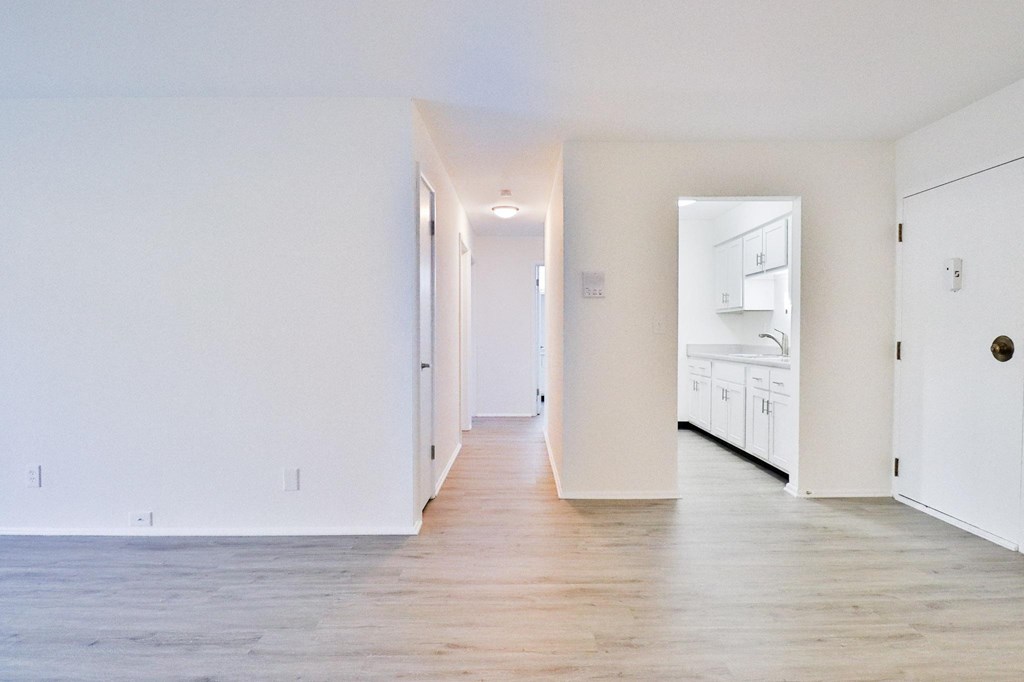 an empty living room with white walls and wood floors