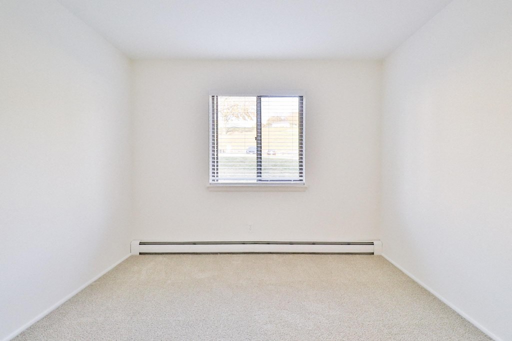 a spacious room with white walls and a window