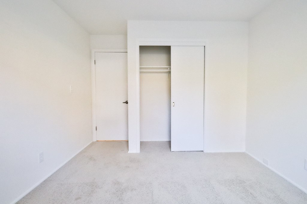 an empty room with white walls and closet doors