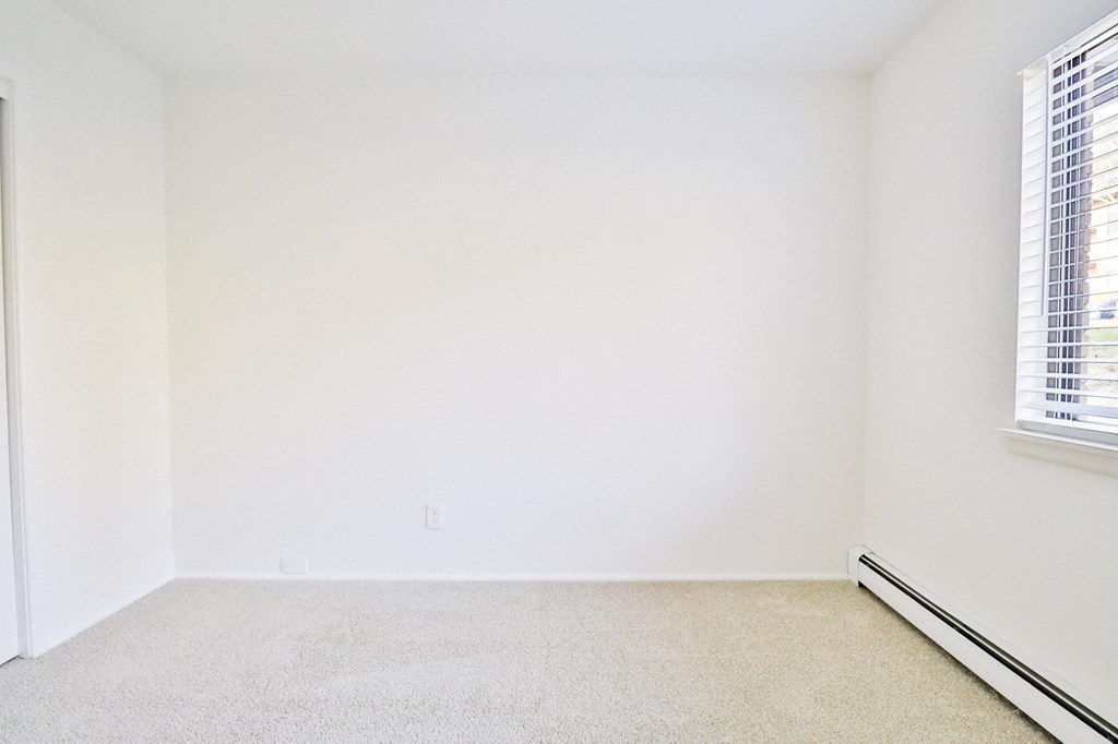 an empty room with white walls and two windows
