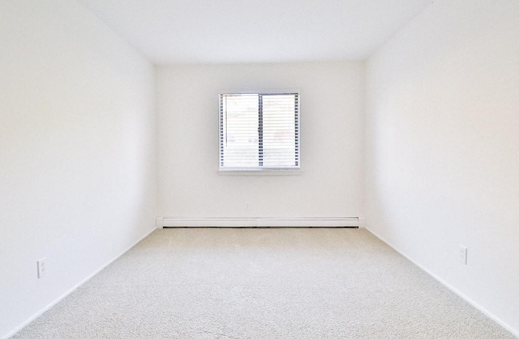an empty room with a window and white walls