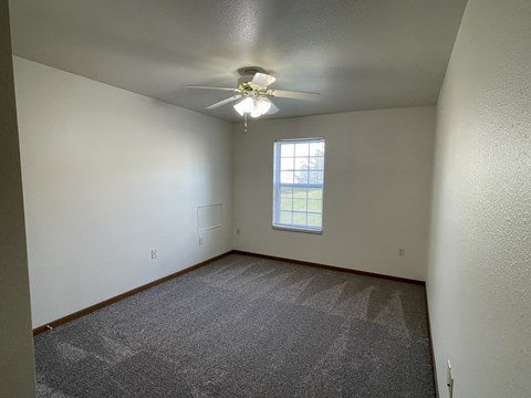 A room with a ceiling fan and a window.