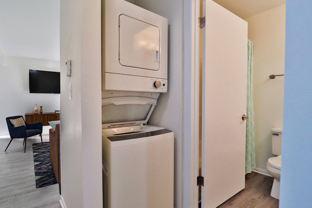 A small, white, built-in fridge in a narrow hallway.