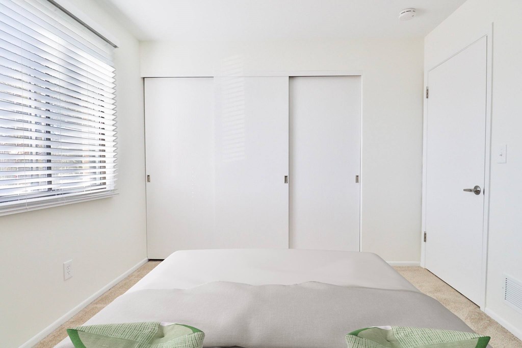 A white bedroom with a bed and two doors.