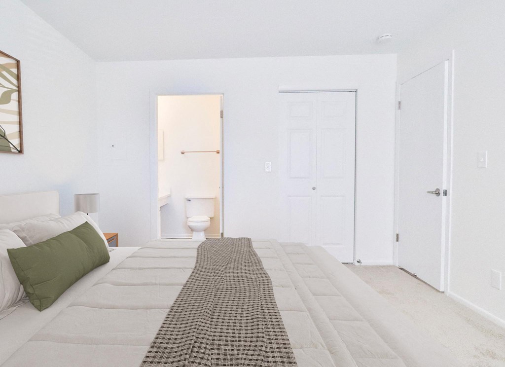 A bedroom with a bed, a toilet, and two doors.