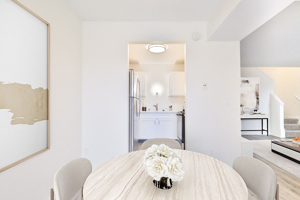 A dining room with a table and chairs and a painting on the wall.
