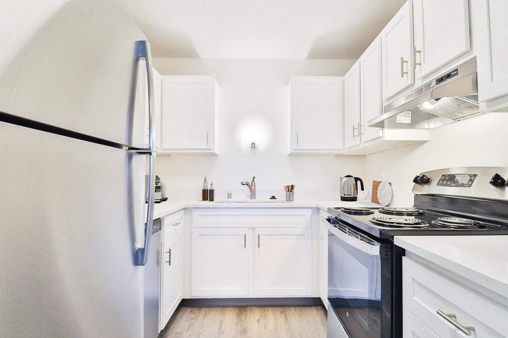 A kitchen with white cabinets and a black refrigerator.