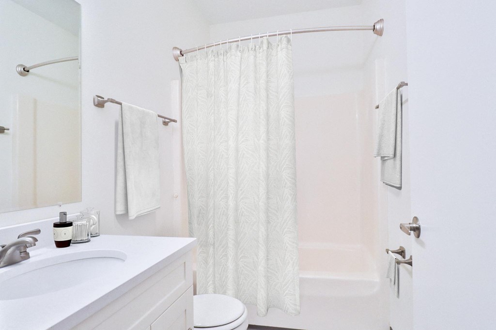 A white bathroom with a toilet, sink, and shower curtain.