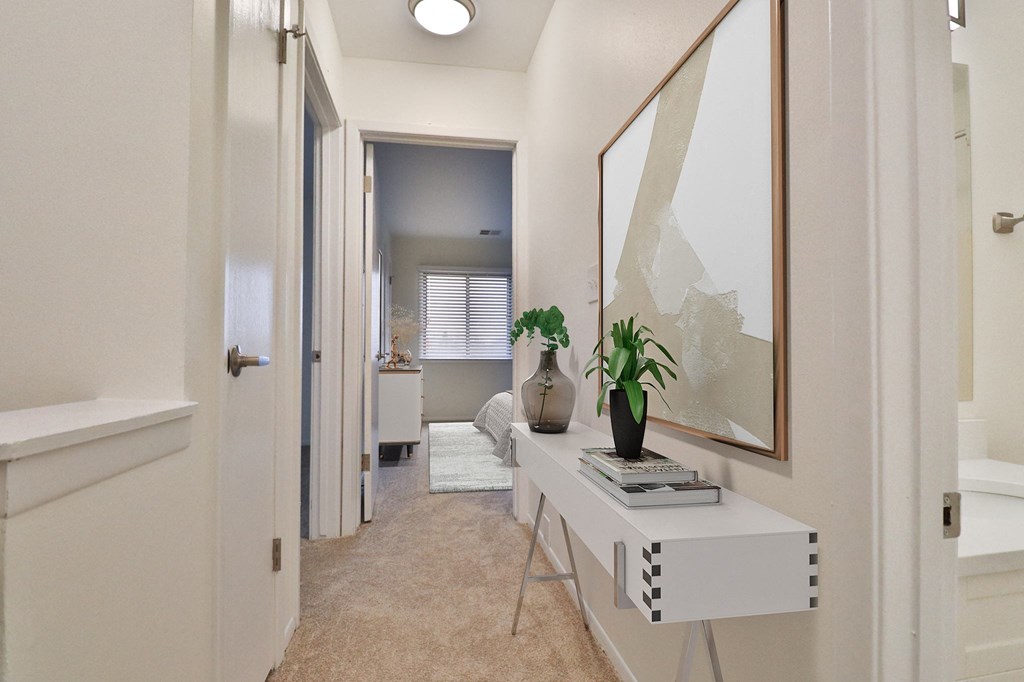 A hallway with a white bench and a mirror on the wall.