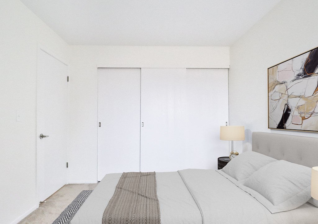 A bedroom with a large bed and a painting on the wall.