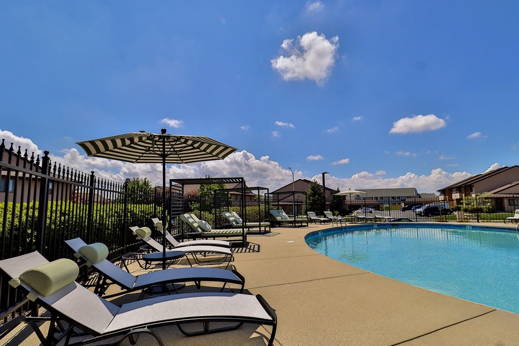 A pool area with sun loungers and a striped umbrella.