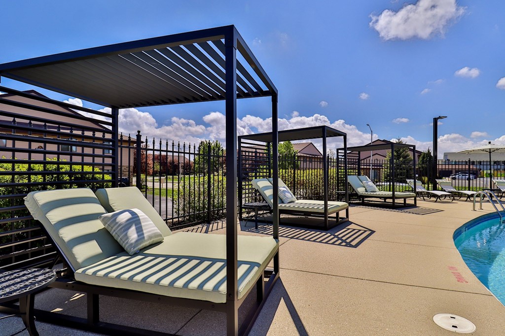 A poolside area with sun loungers and a metal fence.