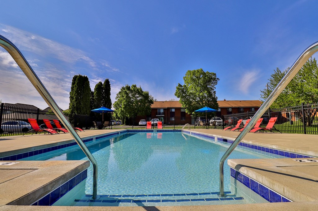 A swimming pool with a blue sky and trees in the background.