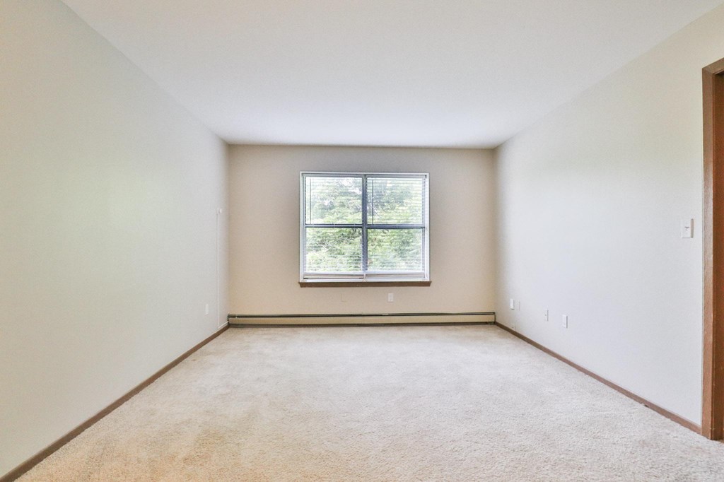 A room with a window and carpeted floor.