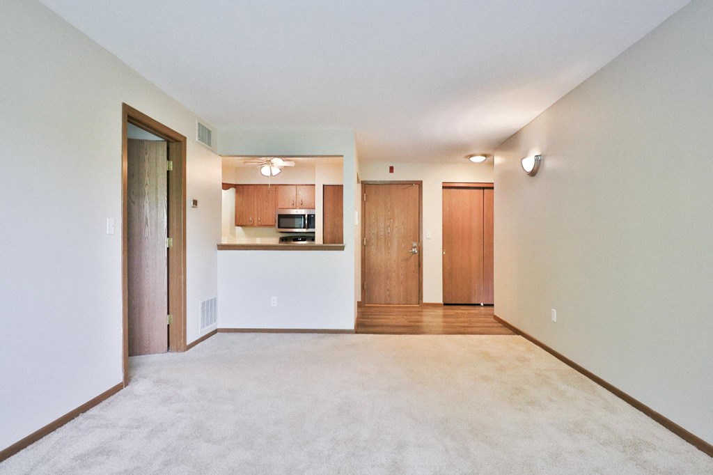 A spacious living room with a kitchen in the background.