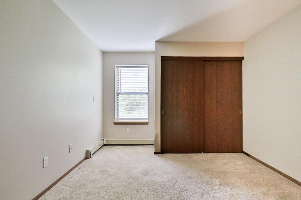 A room with a brown door and a window with blinds.