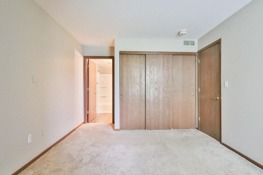 A room with a carpeted floor and two wooden doors.