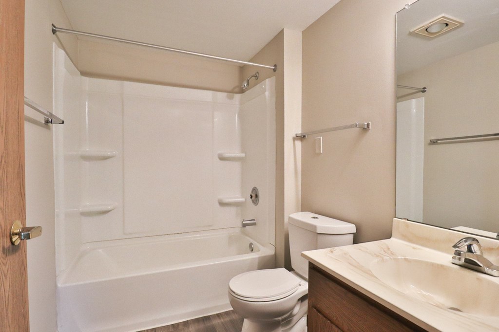 A white toilet sits next to a white bathtub in a bathroom.