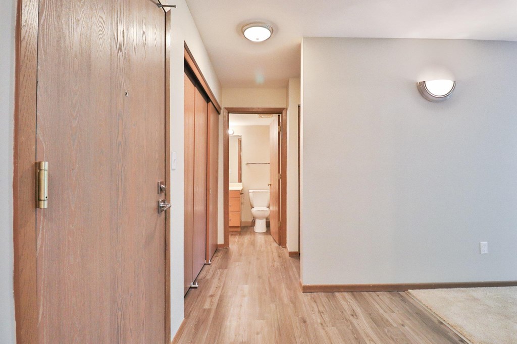 A long hallway with wooden floors and doors on either side.