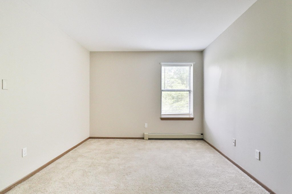 A room with a window and carpeted floor.