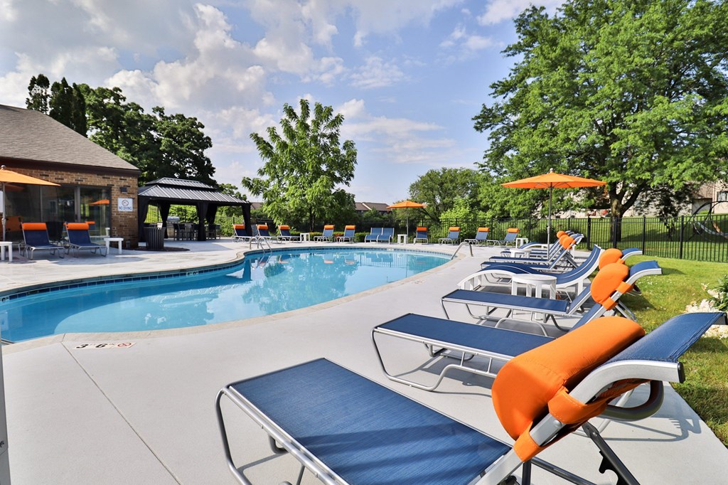 A pool with sun loungers and a gazebo in the background.