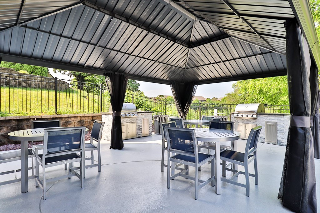 A patio with a table and chairs under a black canopy.