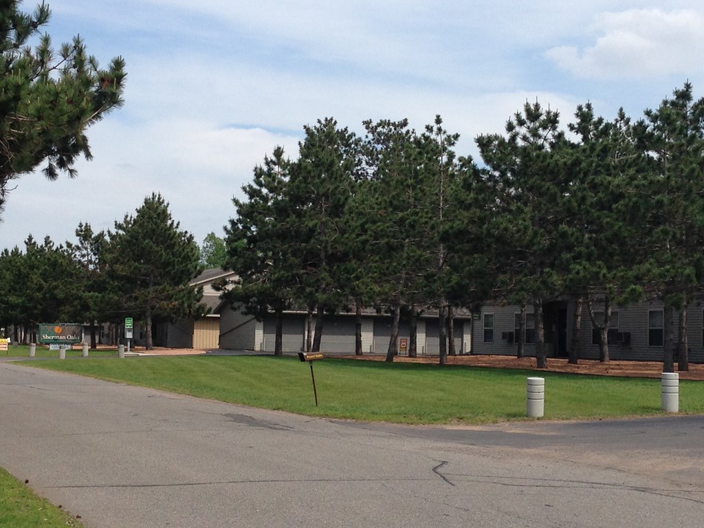 A road with a building and trees in the background.