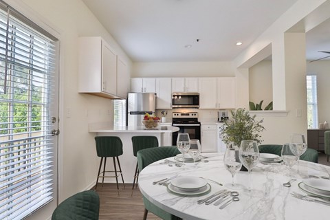 A modern kitchen with a dining table set for two.