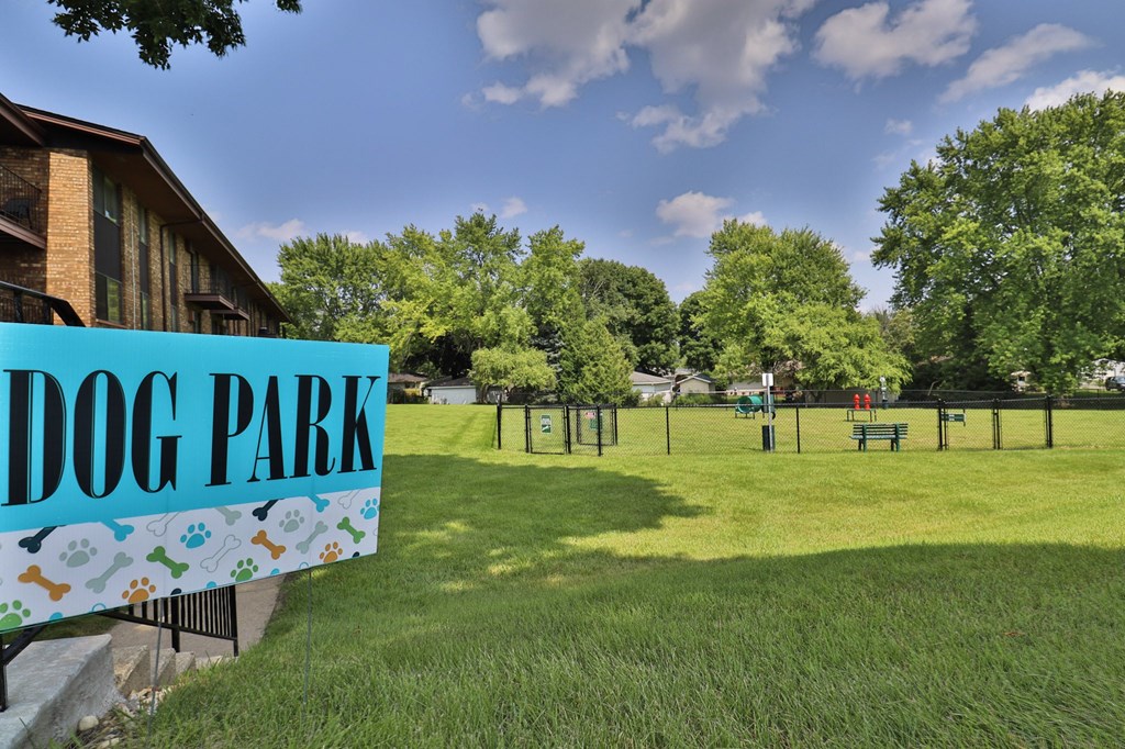 A sign that says Dog Park in front of a green field.