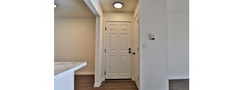 A white door is in a hallway with a light on the wall.