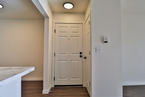 A white door is in a hallway with a light on the wall.