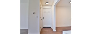 A white door is in a hallway with wood floors.