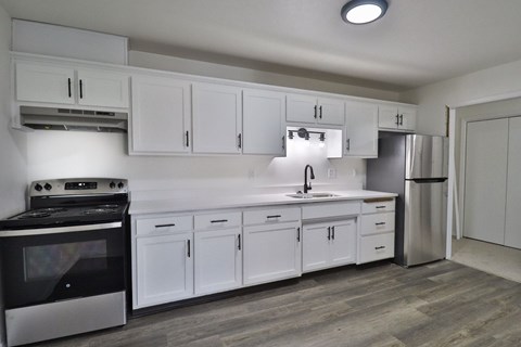 A modern kitchen with white cabinets and a black stove top oven.