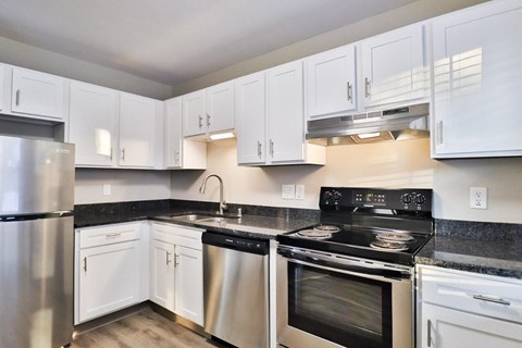 A kitchen with white cabinets and a black stove top.