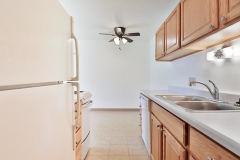 A kitchen with a white refrigerator and a white sink.