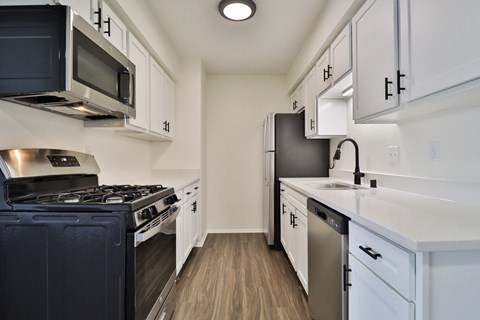 A kitchen with white cabinets and a black stove top oven.
