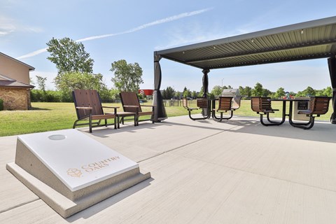 A concrete structure with the word "SALE" written on it is in the foreground of an outdoor seating area with several chairs and tables.