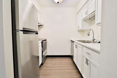 A kitchen with white cabinets and a stainless steel refrigerator.