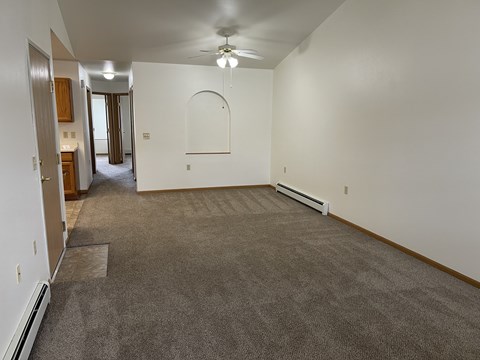 A spacious room with a carpeted floor and a ceiling fan.
