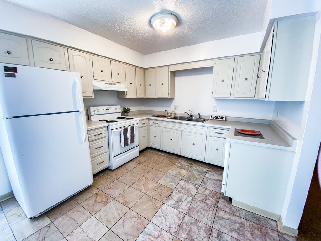an empty kitchen with white appliances and white cabinets