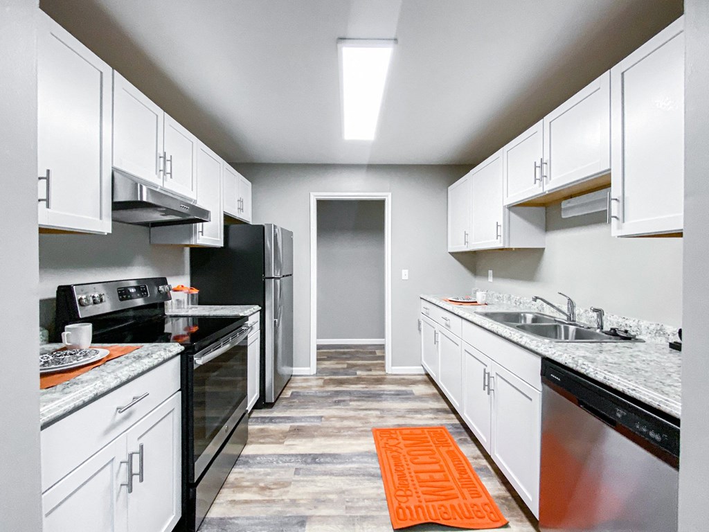 an empty kitchen with white cabinets and black appliances