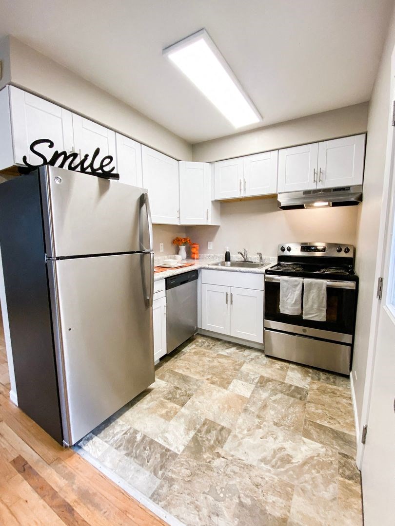 a renovated kitchen with stainless steel appliances and white cabinets