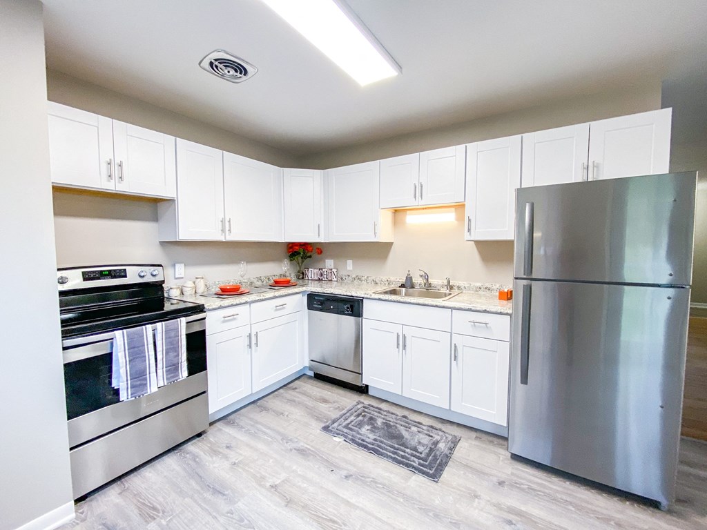 an empty kitchen with stainless steel appliances and white cabinets